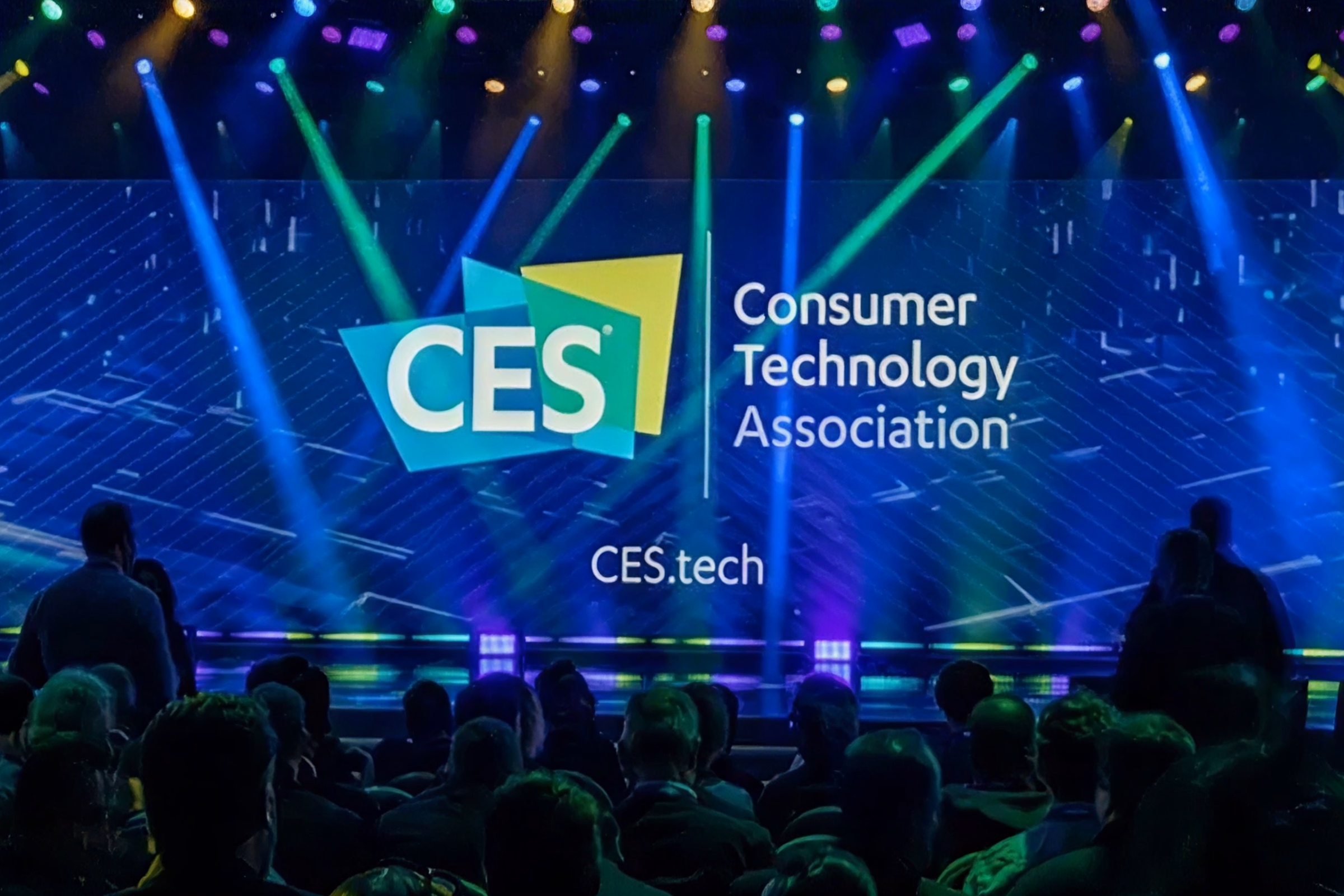 The CES stage at the Consumer Technology Association keynote, lit by green and blue beams over a seated audience.
