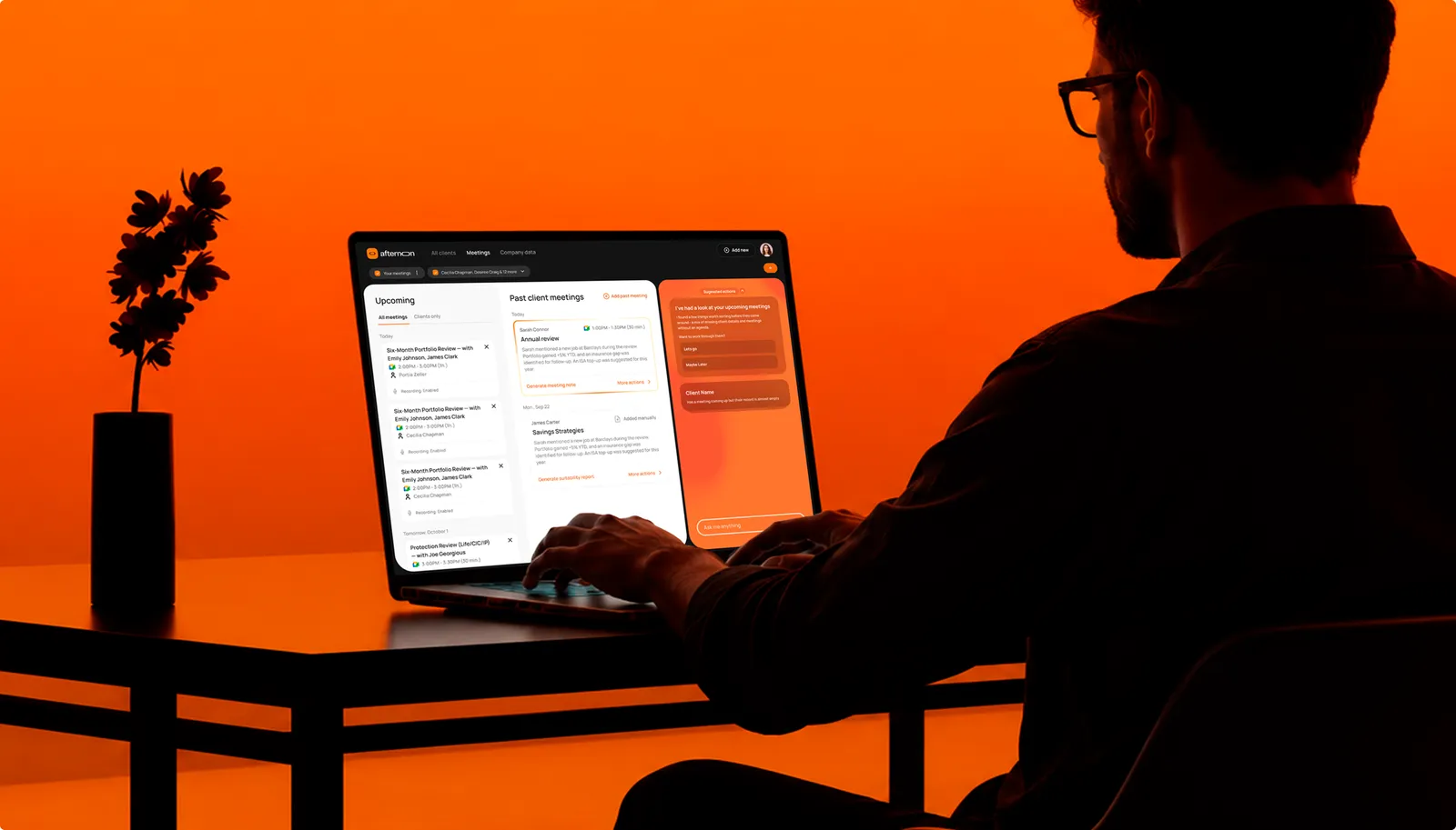 A man at a laptop running the Afternoon meetings dashboard, the room lit orange