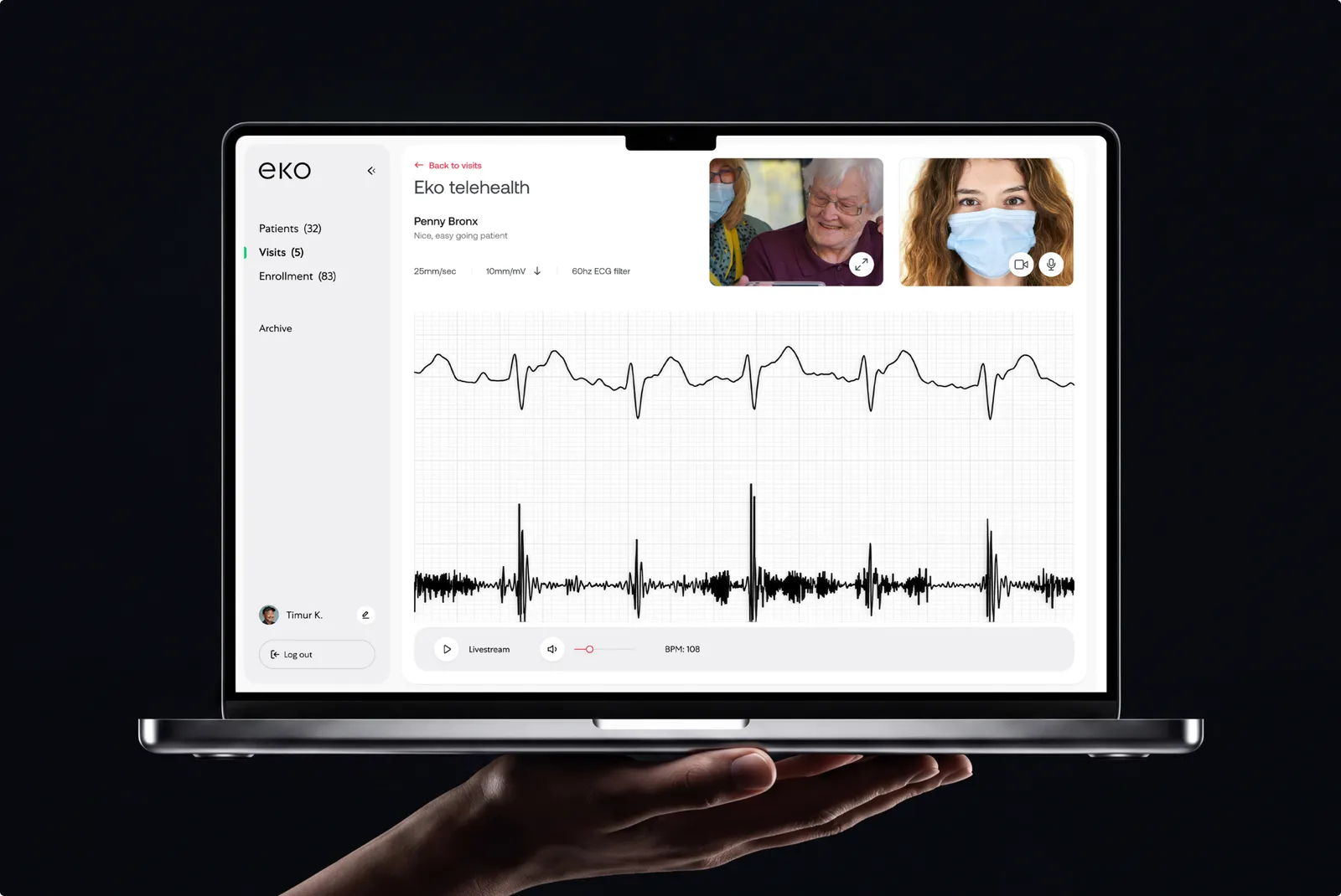 Laptop held in a hand showing the Eko telehealth session for patient Penny Bronx with two video thumbnails and a live ECG waveform, on black