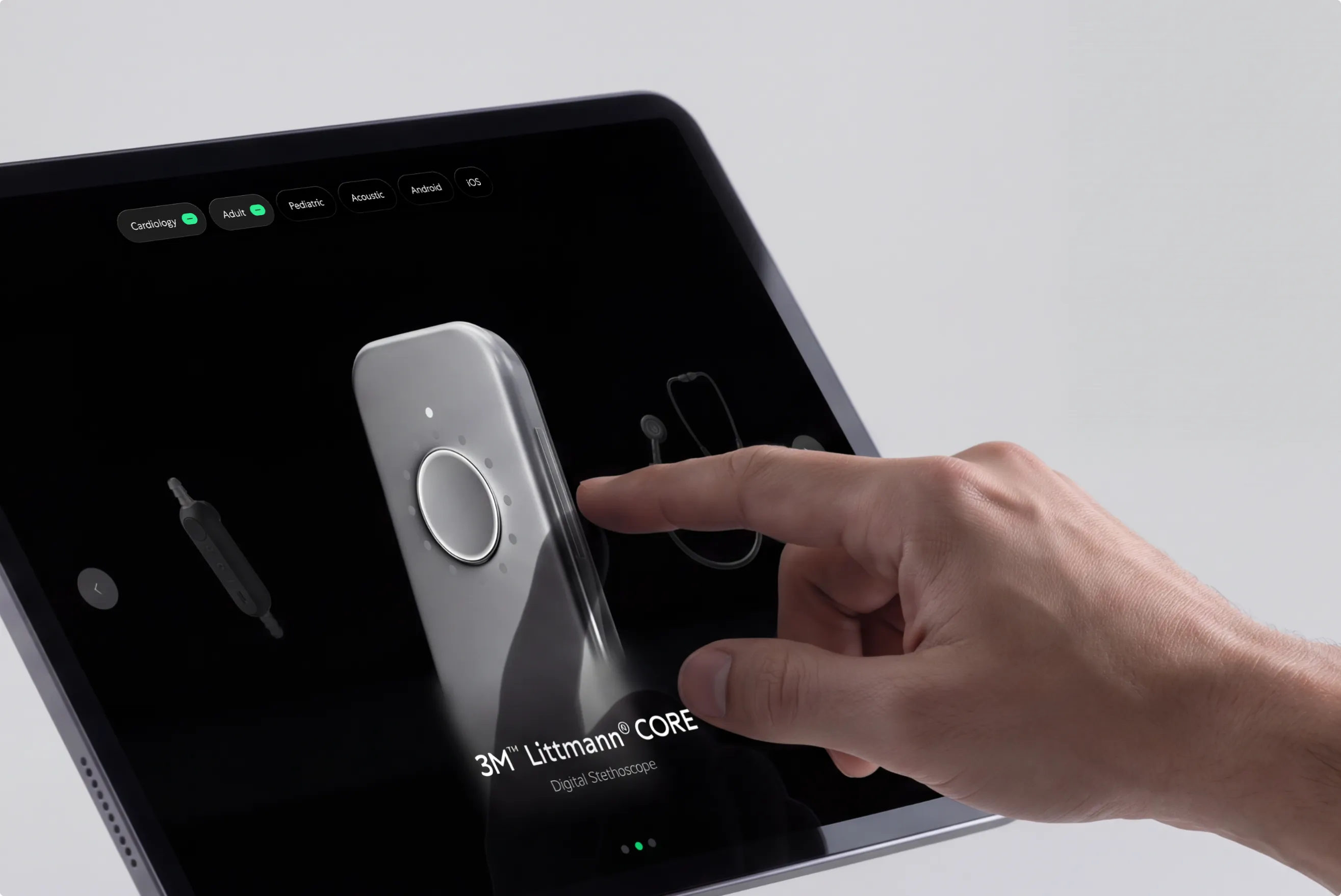 Hand tapping a tablet showing the 3M Littmann CORE Digital Stethoscope device-selection screen, on light gray
