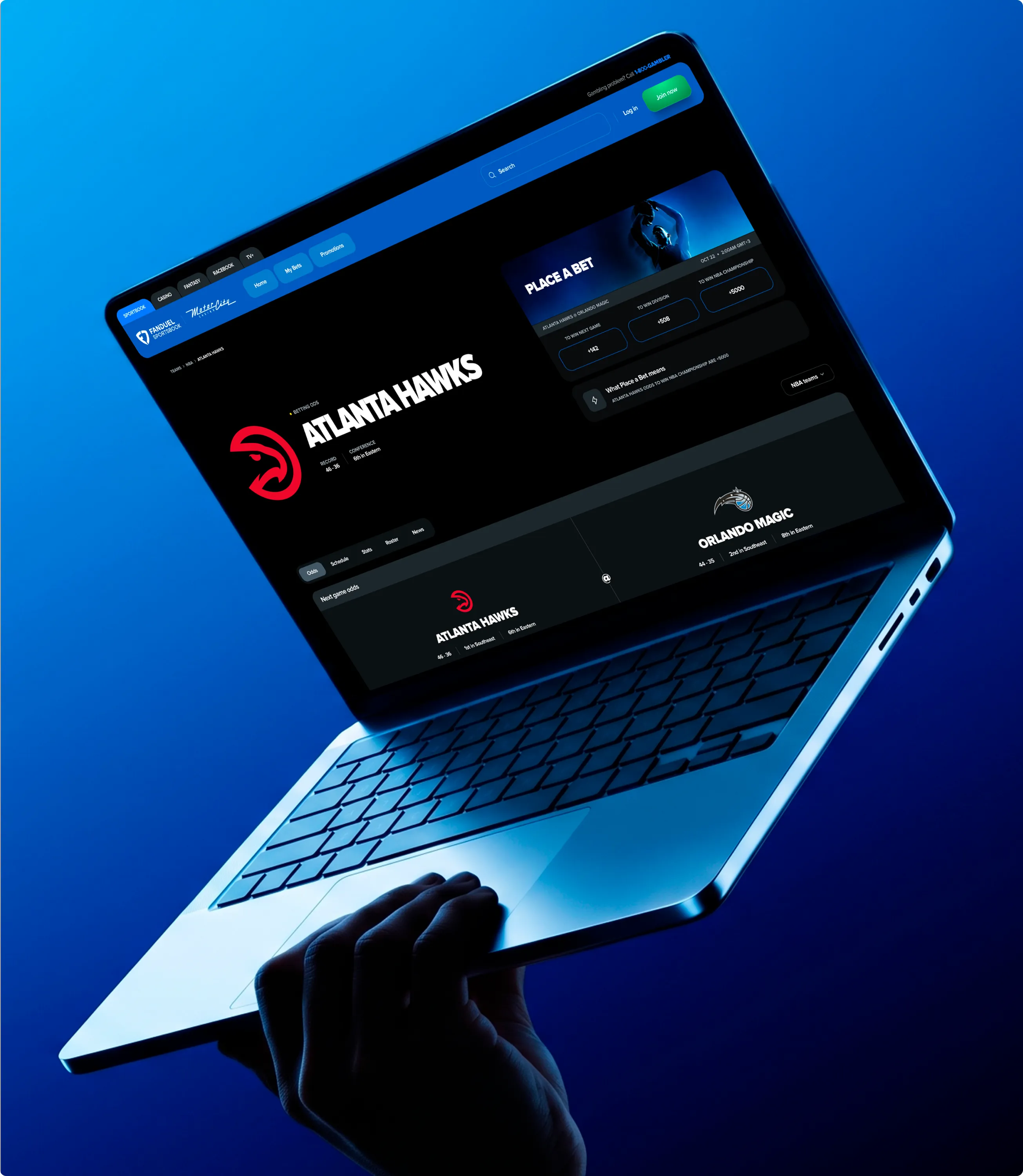 A laptop held in blue light showing the Atlanta Hawks game page with the bet panel open