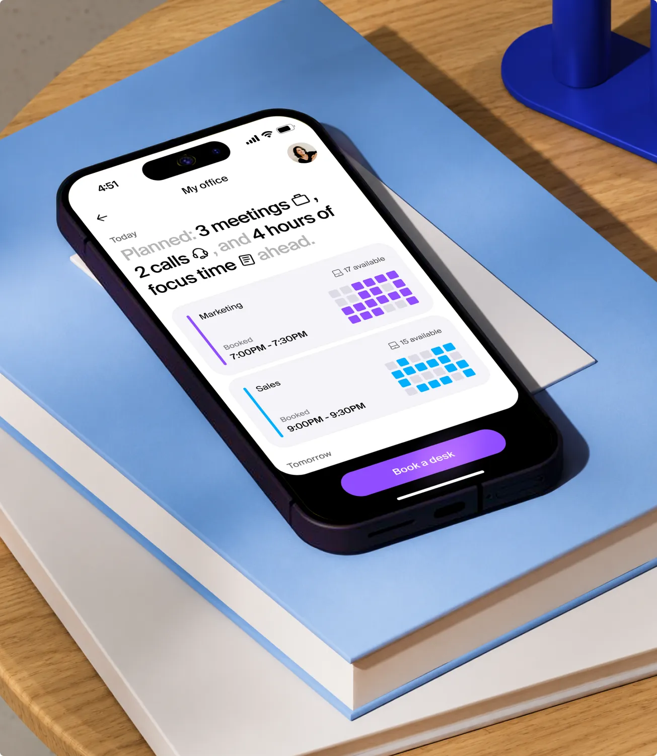 Booking app on a phone: today’s plan — three meetings, two calls and four hours of focus time — over the floor’s desks, with a Book a desk button