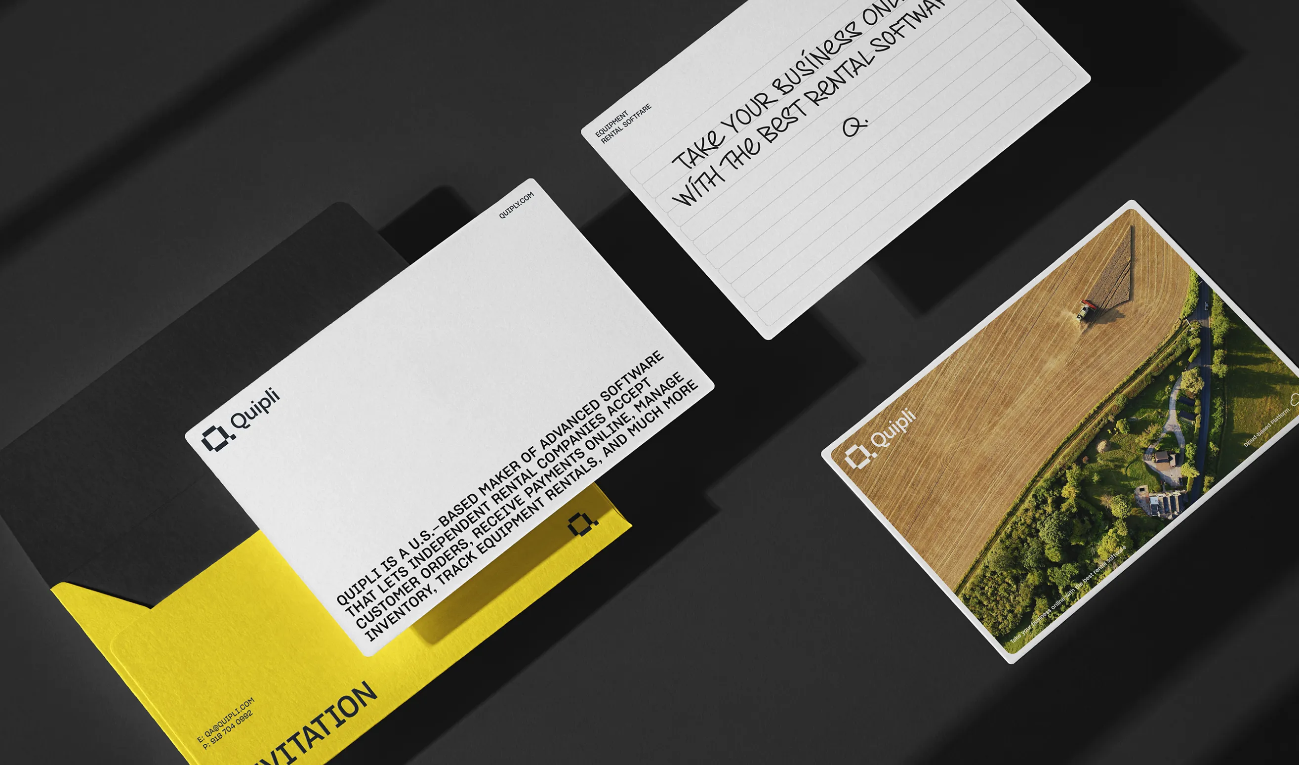 Quipli stationery set with an invitation folder, a ruled note card, and an aerial farmland postcard on a dark surface