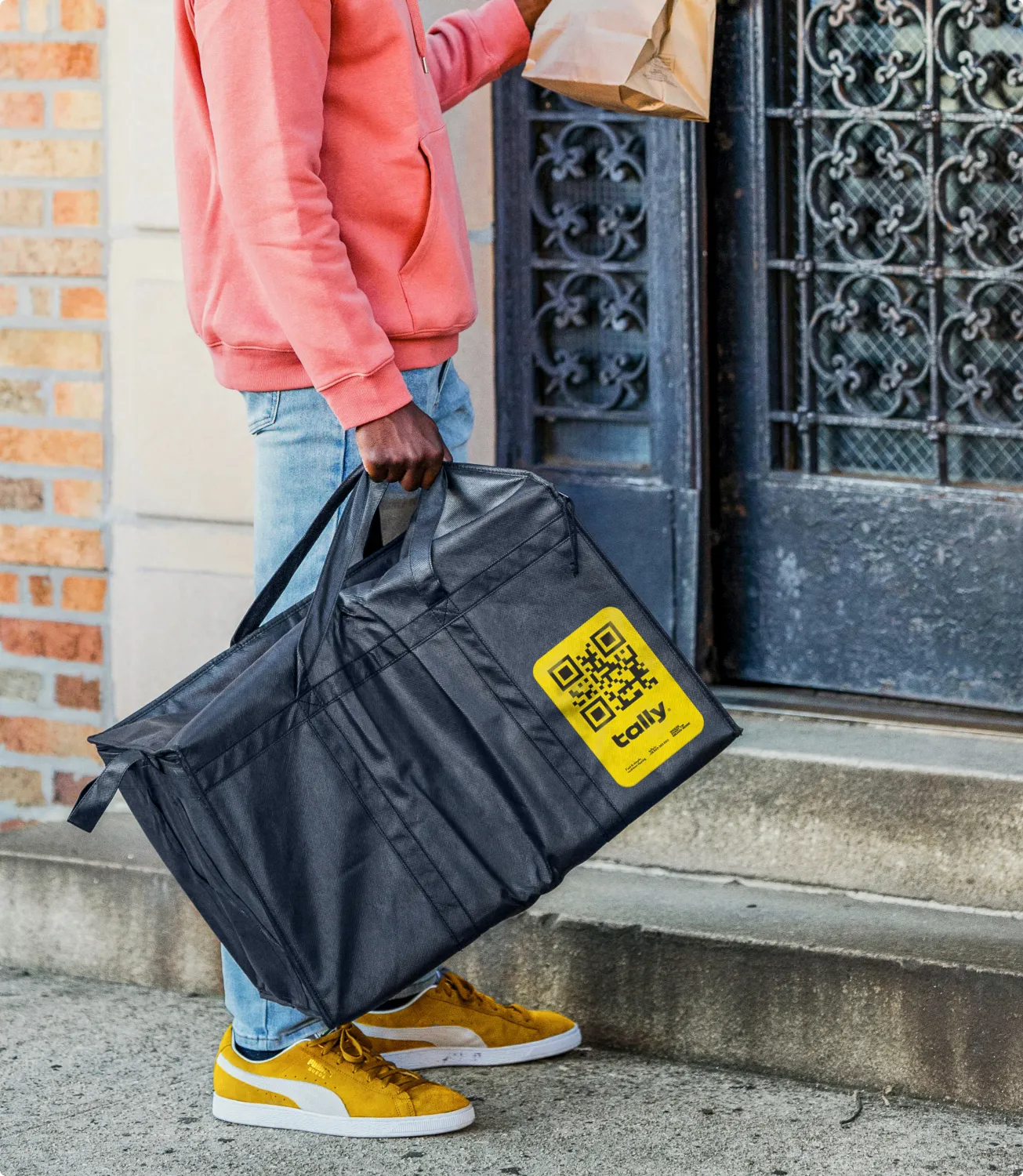 Person carrying a Tally-branded duffel bag on city steps