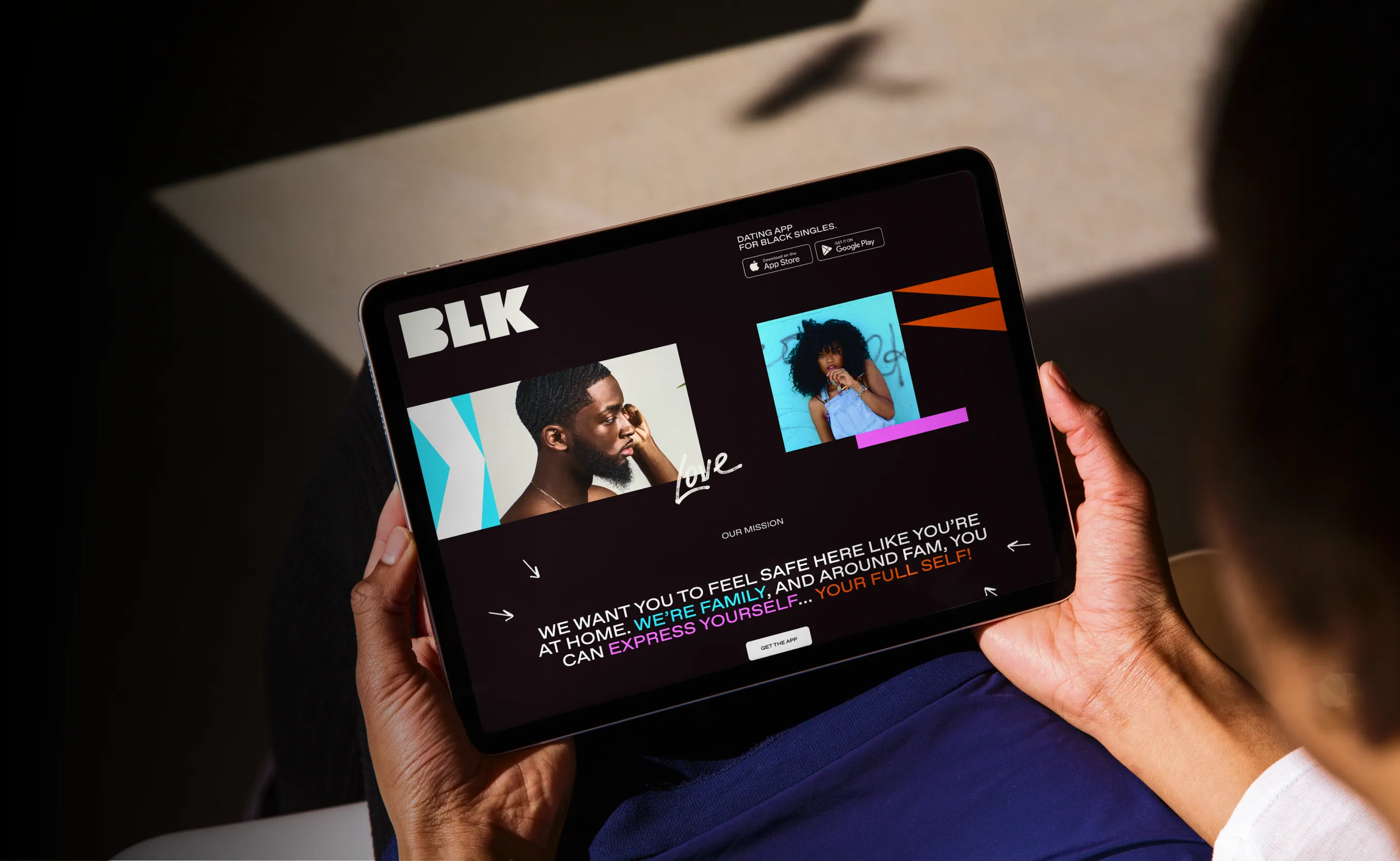 Hands holding a tablet with the BLK dating app website